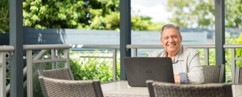 Sydney Bookkeeper working on laptop at outdoor table with trees in background