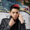 Actor headshot of young Asian male styled hair with red highlights wearing leather jacket and graffiti in background in Glebe, Sydney