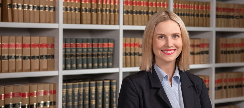 Female lawyer standing in front of law books in Sydney office